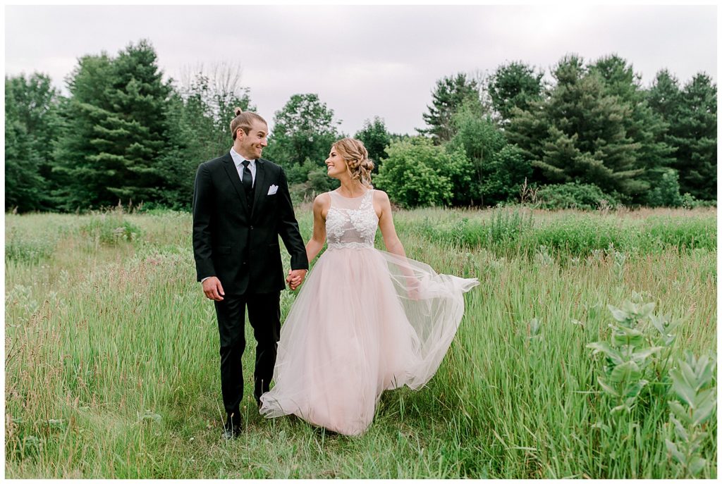 Bride and groom walking in a green field