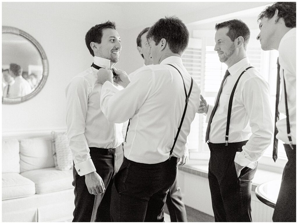 Groomsmen help the groom with his bowtie before his Chatham Bars Inn wedding.