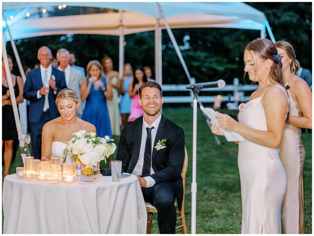 Groom laughs during maid of honor toast.