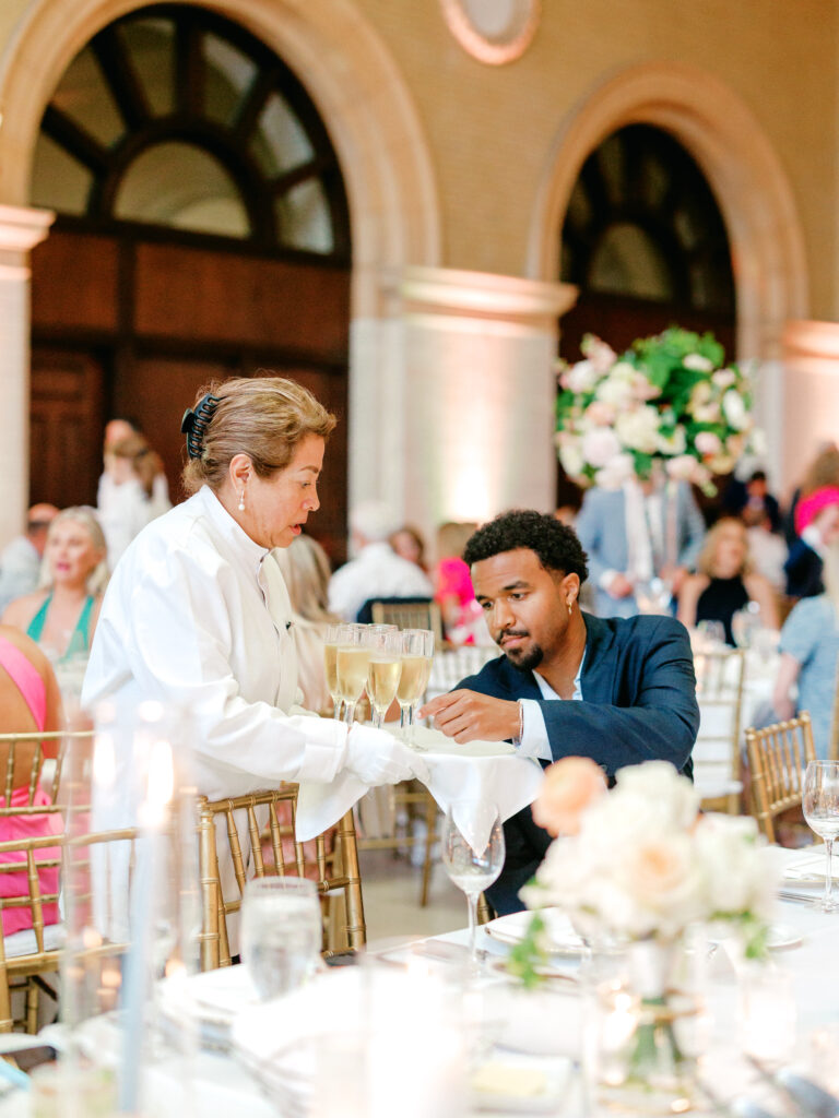 Server offering a wedding guest champagne at dinner at The Depot Minneapolis wedding in Minneapolis, Minnesota